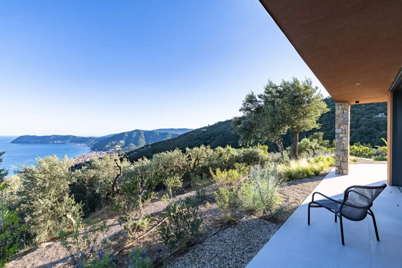 Giardino di ulivi e arbusti mediterranei che scende verso il mare