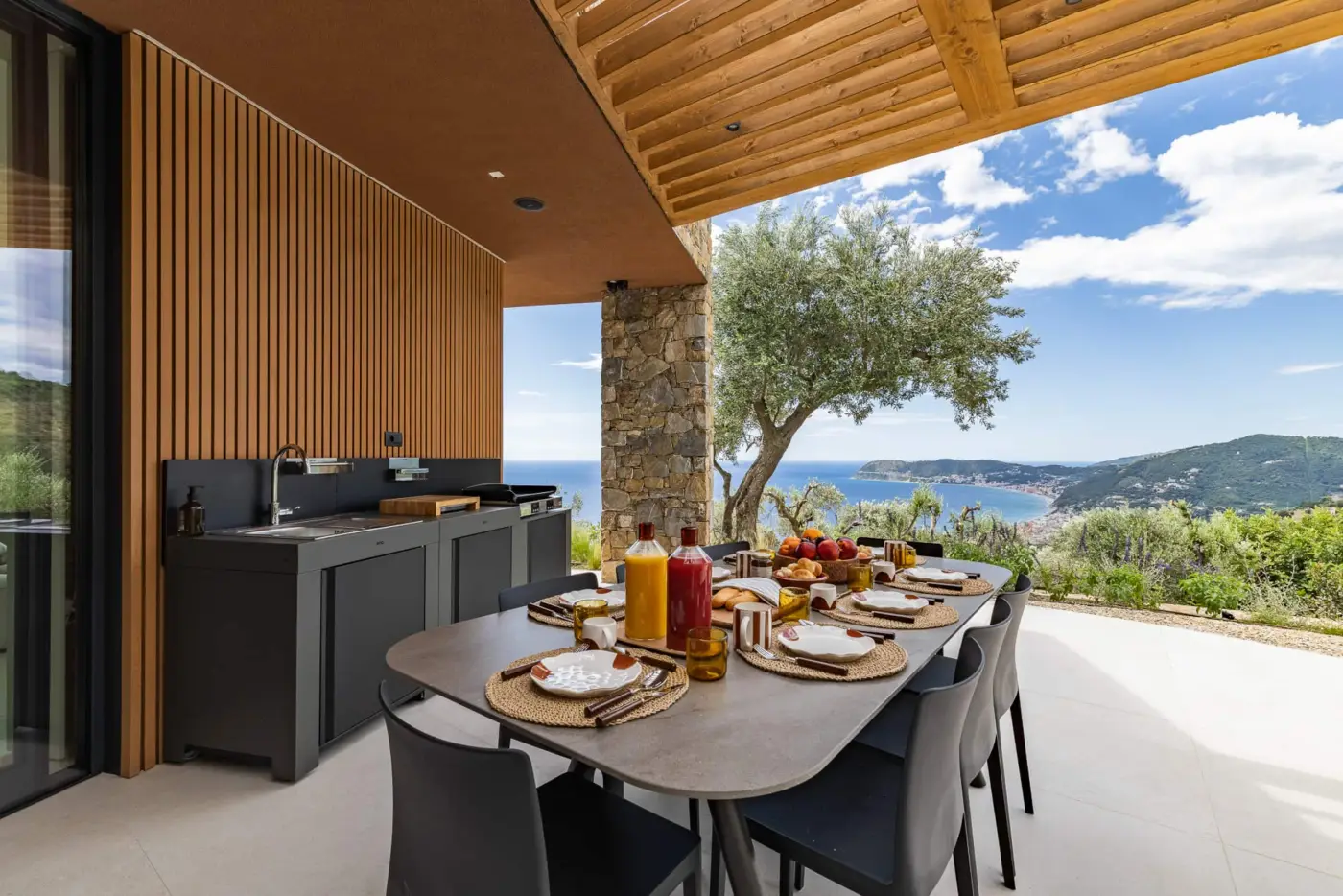 Tavolo del patio apparecchiato per la colazione accanto alla cucina esterna