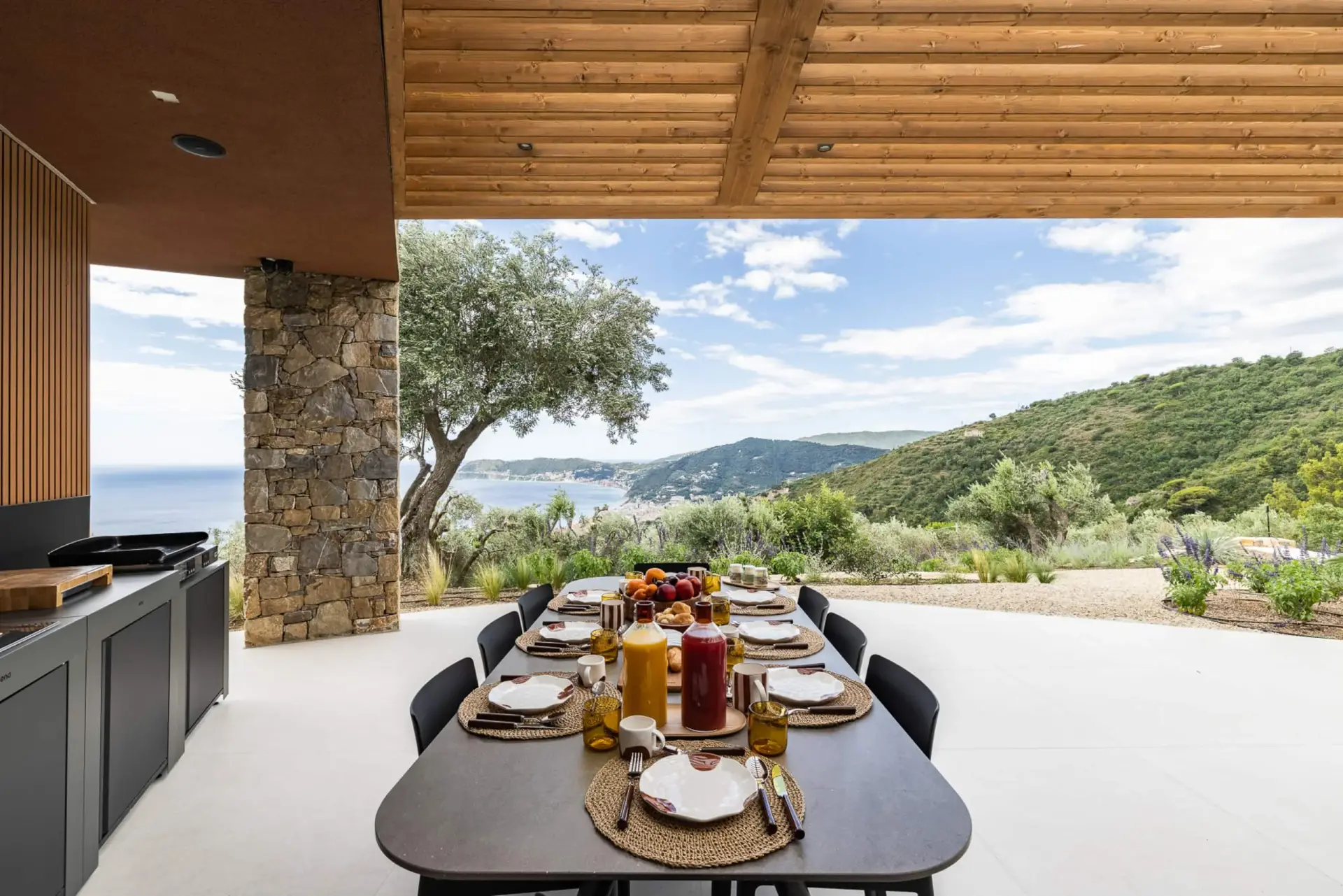 Cucina esterna e lungo tavolo sul patio affacciato sulla costa
