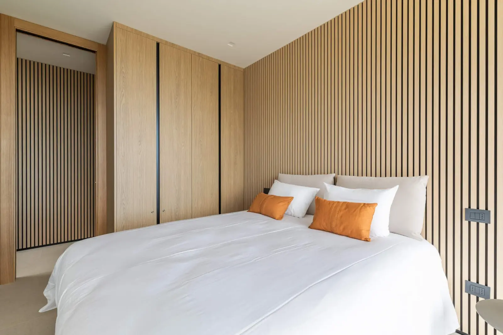 Suite con parete a listelli in rovere, armadio a muro e letto queen-size