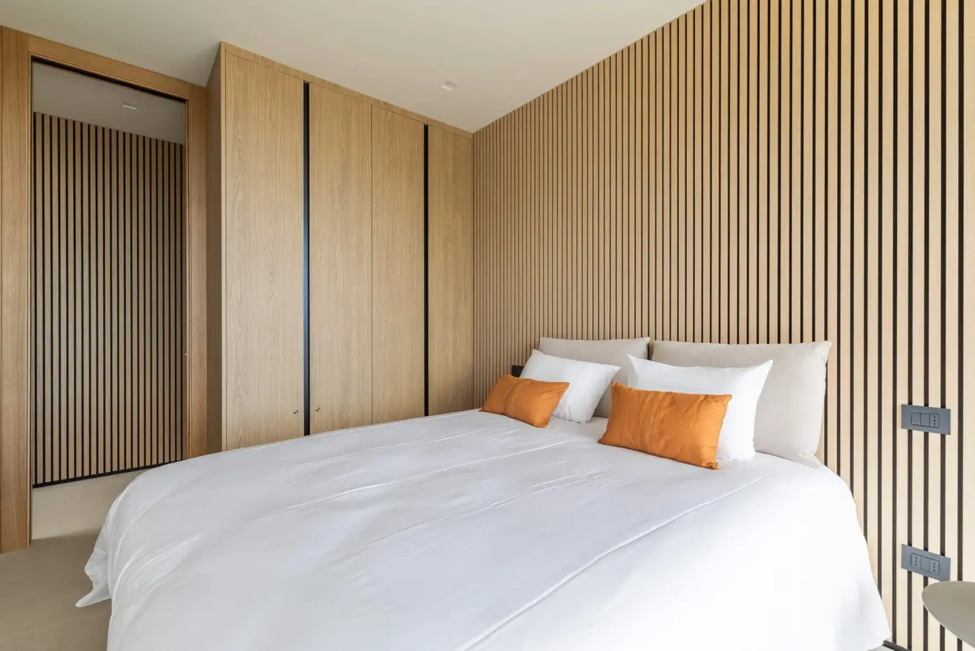 Suite con parete a listelli in rovere, armadio a muro e letto queen-size