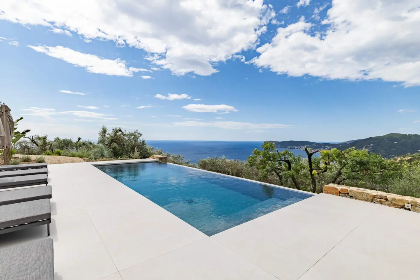 Piscina a sfioro nella luce del mattino, con il mare e la costa all'orizzonte